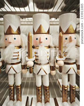 Line of wooden white nutcracker figures with crowns and uniforms on shelf, cheerful winter mood 133911885