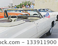 White vintage convertible with small American flag at outdoor car meet, open top and chrome details, sunny day mood 133911900
