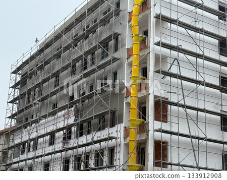 Construction site with workers on scaffolding. Progress, teamwork, and architectural transformation through urban development and renewal. Construction site with workers on scaffolding. Progress, teamwork, and architectural transformation through urban development and renewal. 133912908