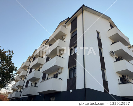 Modern residential building under blue sky. Urban architecture, housing development, and city lifestyle representing modern construction and urbanization trends. 133912937