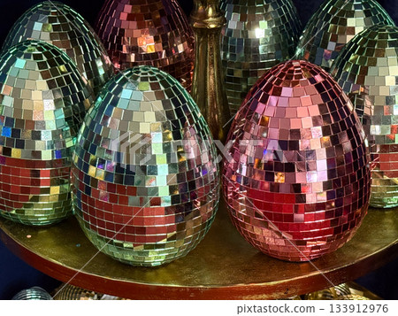 Christmas Disco mosaic egg ornaments arranged together on golden plate under soft lights. Holiday glamour, modern Christmas styling, party sparkle and festive decorative energy. 133912976