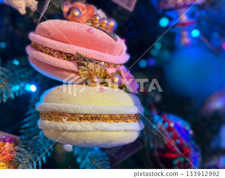 Plush macaron ornaments with pearls and leaves hanging on Christmas tree. Holiday sweetness, festive dessert fantasy, playful decor and magical seasonal celebration mood. Plush macaron ornaments with pearls and leaves hanging on Christmas tree. Holiday sweetness, festive dessert fantasy, playful decor and magical seasonal celebration mood. 133912992