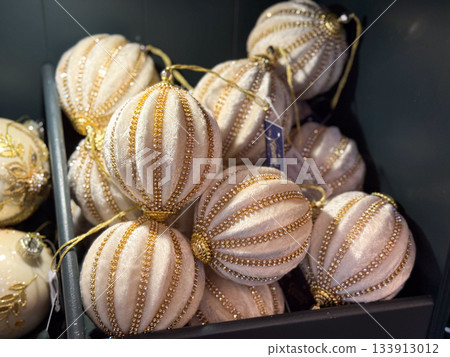 Velvet gold-striped ornaments arranged inside a festive display box. Refined elegance, luxurious decoration and graceful winter charm creating sophisticated holiday atmosphere and sparkling seasonal 133913012