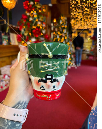 Christmas Nutcracker mug held in a festive holiday shop. Seasonal joy, playful tradition and warm winter storytelling enhancing decorative atmosphere and charming holidays celebration 133913018
