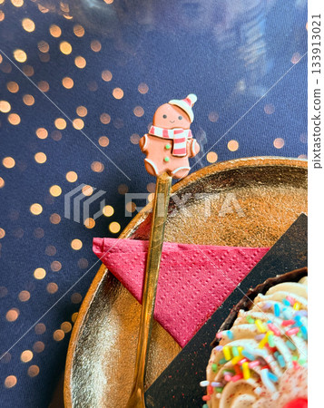 Christmas Gingerbread spoon resting beside a festive dessert. Playful celebration, joyful tradition and warm winter storytelling shaping cheerful holidays mood and charming seasonal atmosphere 133913021