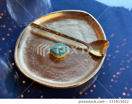 Christmas Tiny iced cookie resting on a golden plate. Gentle celebration, winter calm and holiday simplicity forming delicate seasonal storytelling and warm atmosphere Christmas Tiny iced cookie resting on a golden plate. Gentle celebration, winter calm and holiday simplicity forming delicate seasonal storytelling and warm atmosphere 133913022