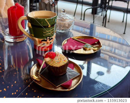 Christmas dessert setting with nutcracker mug and festive cupcake. Warm celebration, seasonal charm and joyful winter storytelling enhancing cozy atmosphere and decorative holiday mood 133913023