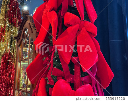 Red velvet bows decorating a festive Christmas tree. Seasonal elegance, joyful tradition and warm holiday atmosphere forming emotional celebration and decorative storytelling for winter magic 133913220