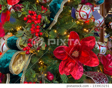 Berries and ornaments nestled among branches of a decorated Christmas tree. Winter atmosphere and holiday charm festive visual storytelling. 133913231