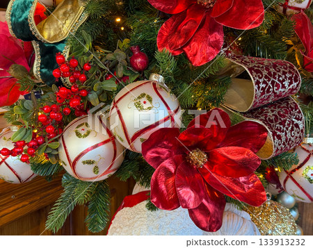 Holiday Christmas ornaments and red florals displayed on evergreen branches. Seasonal mood and decorative elegance spirit of celebration. 133913232