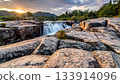 Waterfall cascading over rocks at sunset 133914096