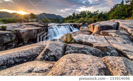 Waterfall cascading over rocks at sunset 133914096