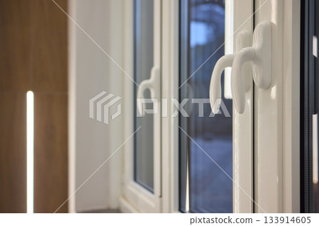 A contemporary window equipped with an open handle that offers a beautiful view of the cityscape 133914605