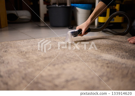 Maintenance technician performs thorough carpet extraction, Professional technician utilizes portable tool to deeply clean and rejuvenate stained commercial carpets Maintenance technician performs thorough carpet extraction, Professional technician utilizes portable tool to deeply clean and rejuvenate stained commercial carpets 133914620