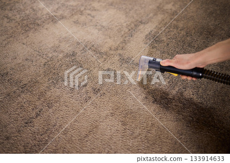Maintenance technician performs thorough carpet extraction, Professional technician utilizes portable tool to deeply clean and rejuvenate stained commercial carpets 133914633