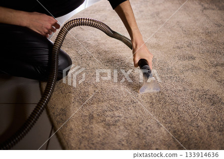 Maintenance technician performs thorough carpet extraction, Professional technician utilizes portable tool to deeply clean and rejuvenate stained commercial carpets 133914636