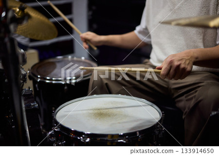 Drummer hands striking snare drum with sticks, captured midperformance showing motion blur, textured drumhead, casual stage clothing and focused groove driving live club energy Drummer hands striking snare drum with sticks, captured midperformance showing motion blur, textured drumhead, casual stage clothing and focused groove driving live club energy 133914650
