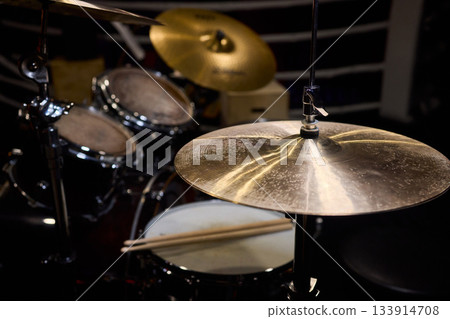 Closeup of shiny percussions, Intimate jazz club setting with textured metal and blurred audience, Glimmering cymbals and drums under warm amber light in cozy jazz venue Closeup of shiny percussions, Intimate jazz club setting with textured metal and blurred audience, Glimmering cymbals and drums under warm amber light in cozy jazz venue 133914708