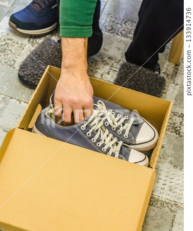 Man Packing Old Sneakers Into Storage Box Man Packing Old Sneakers Into Storage Box 133914736
