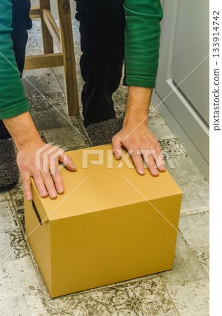 Man Closing Cardboard Storage Box on Floor 133914742