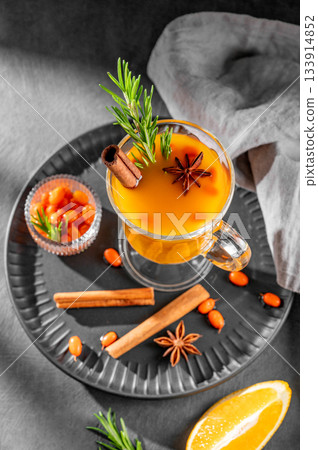 Sea buckthorn herbal tea in a glass on a black plate on a dark background with berries 133914852
