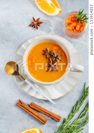 Sea buckthorn herbal tea in a cup on a light background with spices 133914857