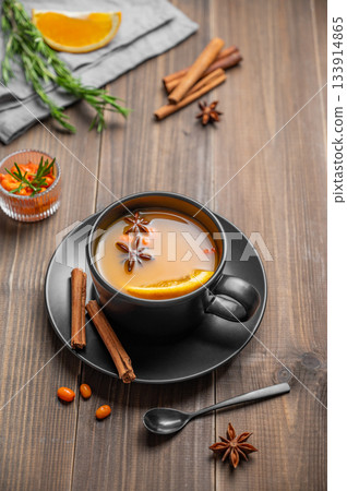 Sea buckthorn herbal tea in a black cup on a wooden background with spices Sea buckthorn herbal tea in a black cup on a wooden background with spices 133914865