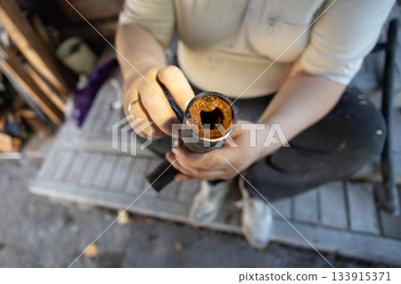 A man holds a section of an old water pipe with visible traces of rust and mineral deposits that reduce the internal diameter and impede water flow An old water pipe with limescale and rust deposits. A man holds a section of an old water pipe with visible traces of rust and mineral deposits that reduce the internal diameter and impede water flow An old water pipe with limescale and rust deposits. 133915371