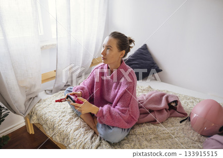 Calm woman intently concentrated on game controller in bedroom 133915515