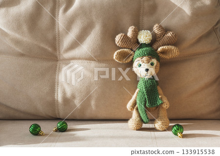 Crocheted Reindeer with Christmas Gift Box and Ornaments on Cozy Holiday Background 133915538