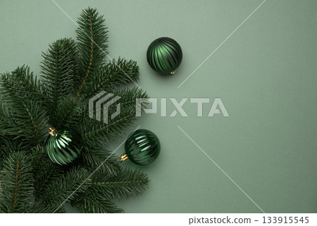 Green Christmas Ornaments Hanging on Pine Branches over Muted Green Background 133915545