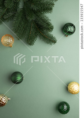 Fir Tree Branch with Green and Golden Christmas Ornaments on Green Background in Festive Flat Lay 133915547