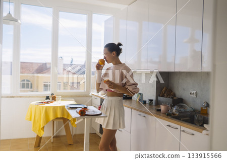 Relaxed woman standing by table with fruit and warm light Relaxed woman standing by table with fruit and warm light 133915566