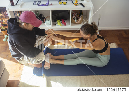 Woman performing flexibility exercises with instructor guidance Woman performing flexibility exercises with instructor guidance 133915575