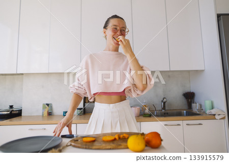 Lively scene with woman savoring orange and smiling broadly Lively scene with woman savoring orange and smiling broadly 133915579