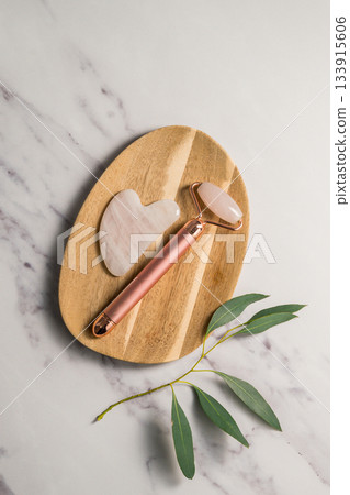 Rose quartz gua sha tool and face massage roller, beauty abstract photo. Top view Rose quartz gua sha tool and face massage roller, beauty abstract photo. Top view 133915606