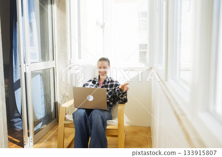 Woman in jeans relaxing on balcony while working remotely Woman in jeans relaxing on balcony while working remotely 133915807