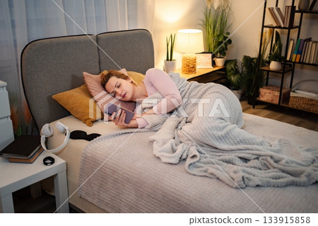 Woman using phone in bed late at night Woman using phone in bed late at night 133915858