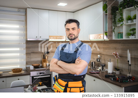 Handyman standing with arms crossed in kitchen looking at camera 133915895