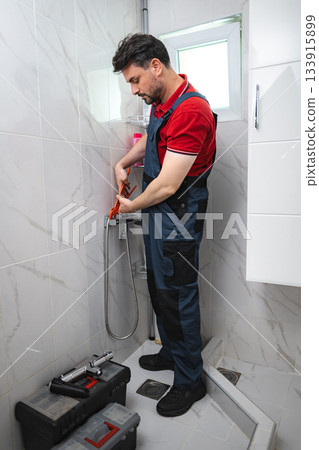 Plumber fixing shower faucet in modern bathroom 133915899