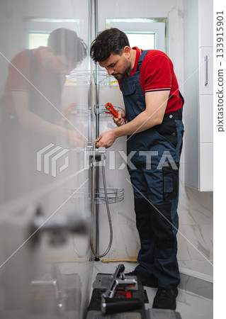 Plumber Installing Shower Faucet in Modern Bathroom 133915901
