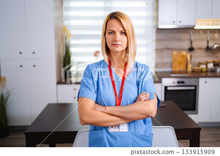 Serious nurse standing with arms crossed in kitchen 133915909
