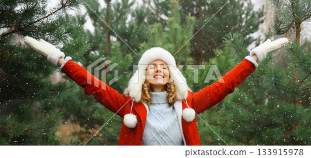 Winter day, happy smiling young woman enjoys snow, warm weather against Christmas tree 133915978