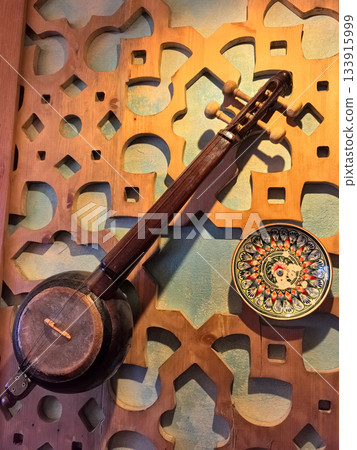 Musical instrument displayed against intricate wooden wall design Musical instrument displayed against intricate wooden wall design 133915999