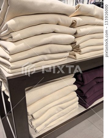 Neatly folded clothes displayed on a modern retail shelf in a clothing store Neatly folded clothes displayed on a modern retail shelf in a clothing store 133916000