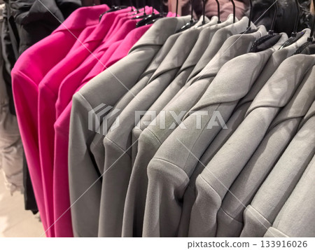Stylish gray and pink garments hanging on display in a chic retail store Stylish gray and pink garments hanging on display in a chic retail store 133916026