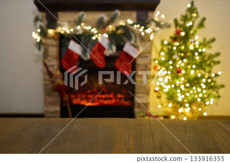 Cozy Holiday Fireplace. Festive fireplace with stockings, garland, and a lit Christmas tree 133916355