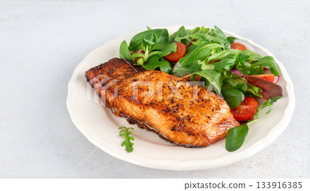 Grilled salmon fillet with fresh green vegetables salad tomatoes on a white background. Healthy low-carb meal. Keto diet Grilled salmon fillet with fresh green vegetables salad tomatoes on a white background. Healthy low-carb meal. Keto diet 133916385