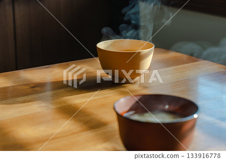 Breakfast scene with steaming miso soup and a wooden table in the morning light 133916778