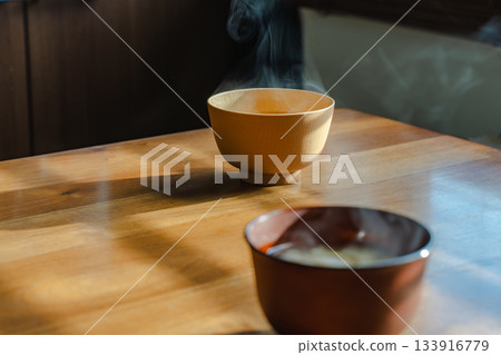 Breakfast scene with steaming miso soup and a wooden table in the morning light 133916779